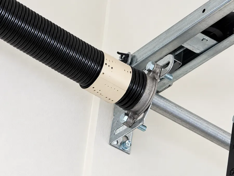Close-up of the stationary cone at the end of a torsion spring, bolted to the center bracket above the door